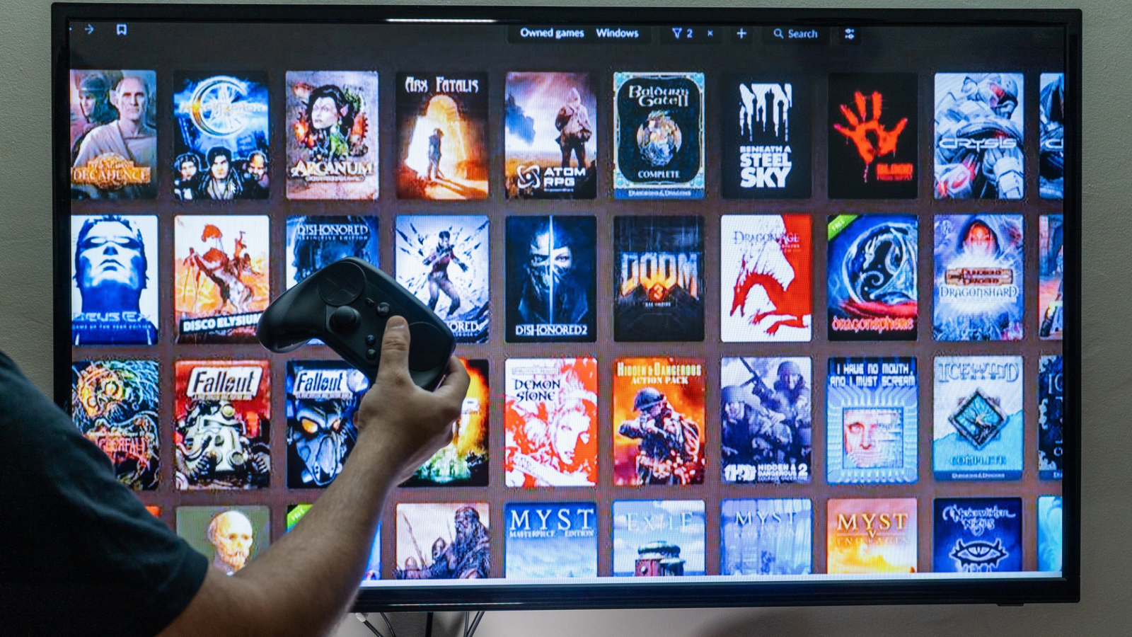person håller steamkontroll framför en tv