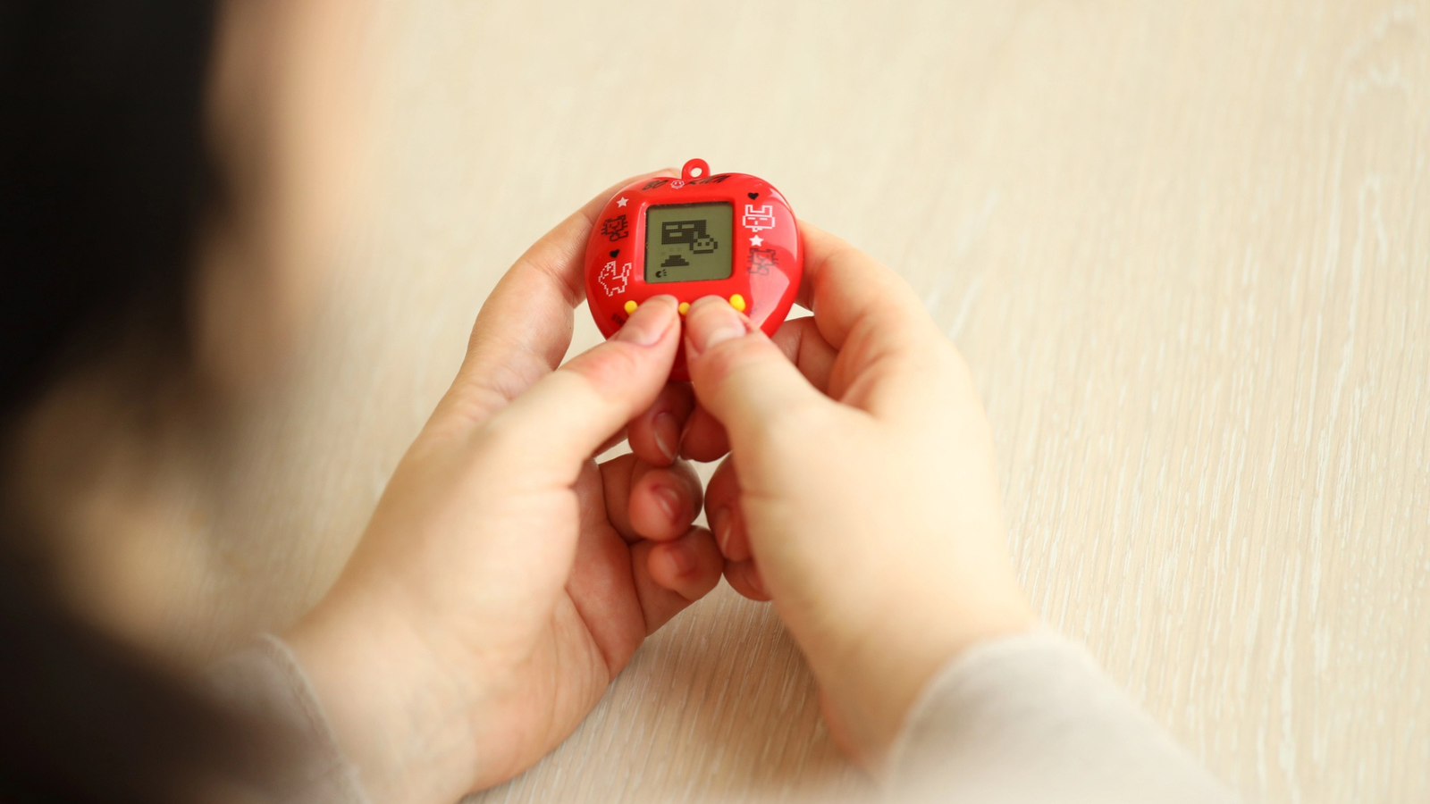 person som håller i en klassisk tamagochi